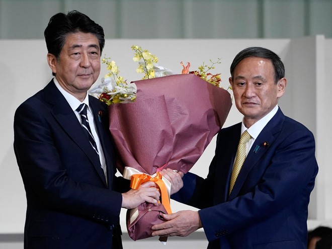 Ông Abe nhận hoa từ ông Suga (phải) sau cuộc bầu chọn lãnh đạo đảng LDP ngày 14/9.
