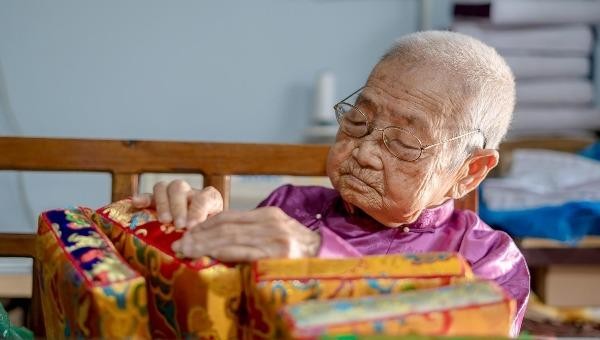 Cụ Huệ gần trăm tuổi vẫn miệt mài gìn giữ nghề làm gối trái dựa cung đình (Ảnh: Éternité Việt Nam). 