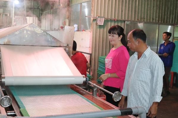 Vợ chồng bà Phan Thị Kim Pha bên dây chuyền sản   xuất bánh tráng Tài Lộc.