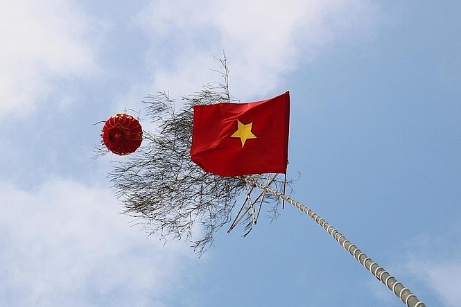 Trên ngọn mỗi cây nêu truyền thống là lá cờ Tổ quốc kiêu hãnh tung bay trong gió xuân. 