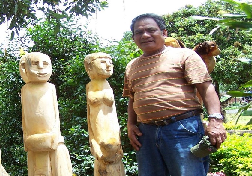 NNƯT Ksor Hnao bên những bức tượng nhà mồ do ông sáng tạo ra.