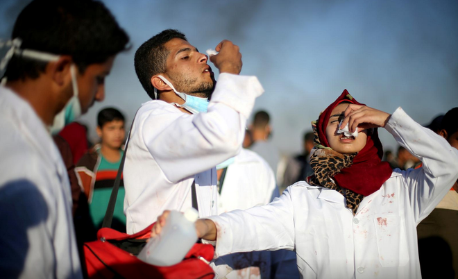 Các nhân viên y tế Palestine tự cứu chữa sau khi bị nhiễm khói hơi cay do binh lính Israel bắn ra
(ảnh Reuters).