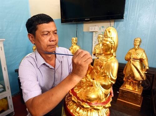 Nghệ nhân Lê Bá Chung bên một sản phẩm tượng mạ vàng. 