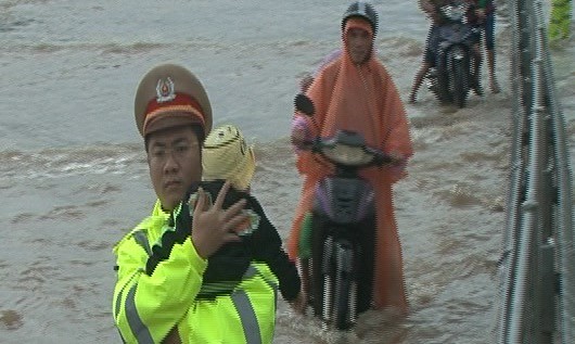Lực lượng CSGT đưa em nhỏ qua đoạn ngập lụt