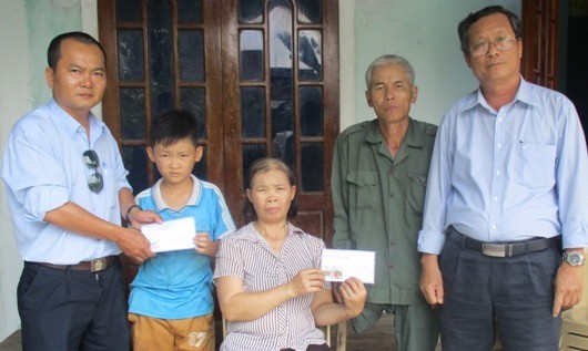 Tác giả (đứng bên trái) và thầy giáo Nguyễn Thuận Nam (đứng bên phải) trao tiền bạn độc cho anh Hà, chị Lơn và cháu Lĩnh