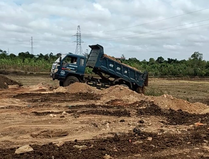 Xe tải mang logo doanh nghiệp Long Tiến ngang nhiên đổ đất san lấp đất lúa giữa ban ngày.
