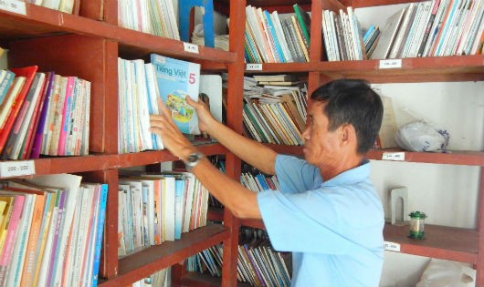 Ông Hưng sắp xếp lại tủ sách trong thư viện của gia đình.