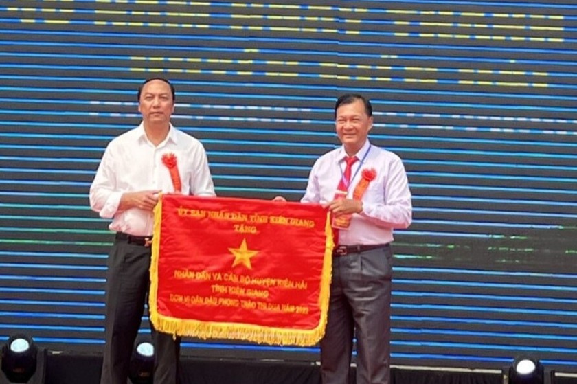 Ông Lâm Minh Thành (bên trái), Chủ tịch UBND tỉnh Kiên Giang tặng cờ cho quân dân và cán bộ huyện Kiên Hải - đơn vị dẫn đầu phong trào thi đua năm 2022.